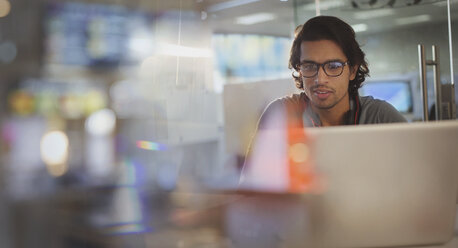 Focused businessman working at laptop in office - HOXF03448