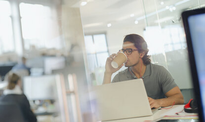 Kreativer Geschäftsmann trinkt Kaffee, arbeitet am Laptop im Büro - HOXF03457