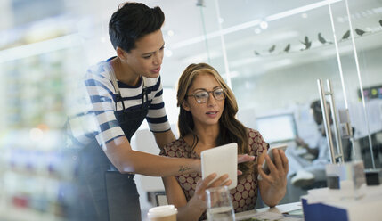 Kreative Geschäftsfrauen nutzen Smartphone und digitales Tablet im Büro - HOXF03480