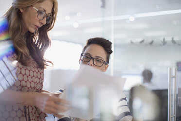 Businesswomen discussing paperwork in office - HOXF03487