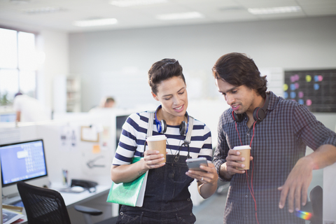 Kreative Geschäftsleute, die im Büro Kaffee trinken und ihr Smartphone benutzen, lizenzfreies Stockfoto