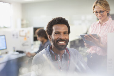 Portrait smiling, confident creative businessman with headphones in office - HOXF03511