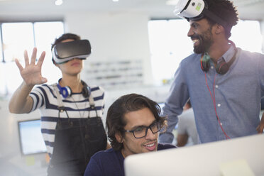 Computer programmers testing virtual reality simulator glasses in office - HOXF03512