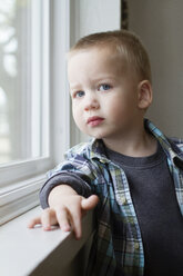 Porträt eines süßen Jungen, der zu Hause am Fenster steht - CAVF45732