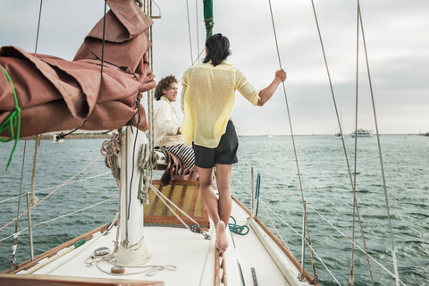 Freunde unterhalten sich während der Fahrt im Segelboot, lizenzfreies Stockfoto