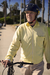 Lächelnder Mann schaut weg, während er mit dem Fahrrad im Park steht - CAVF45754