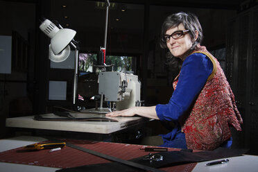 Portrait of woman using sewing machine in workshop - CAVF45779