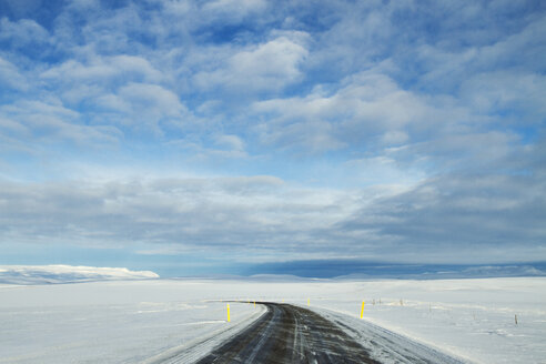 Leere Straße inmitten eines verschneiten Feldes gegen den Himmel - CAVF45845