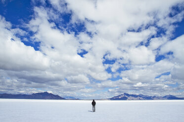 Rückansicht eines Mannes, der auf einem verschneiten Feld vor einem bewölkten Himmel steht - CAVF45853