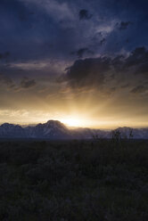 Scenic view of grassy field against mountains during sunset - CAVF45892