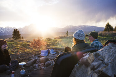 Freunde unterhalten sich beim Sitzen auf dem Campingplatz gegen den Himmel - CAVF45896