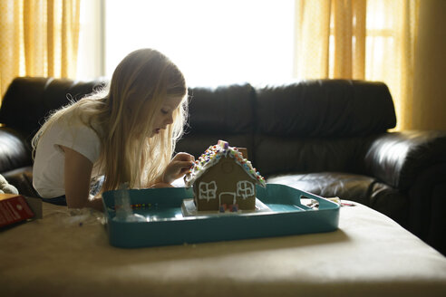Mädchen dekoriert Spielzeughaus auf dem Sofa zu Hause - CAVF45928