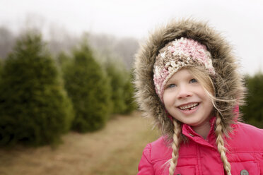 Cheerful girl looking away while standing in pine tree farm - CAVF45952