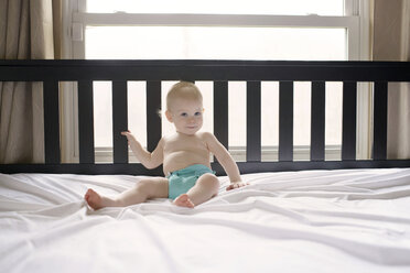 Portrait of cute boy sitting on bed - CAVF45971