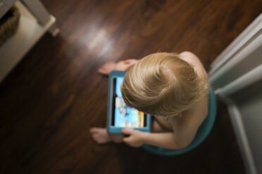 Hochformatige Ansicht eines Jungen, der einen Tablet-Computer benutzt, während er zu Hause auf dem Töpfchen sitzt - CAVF46036