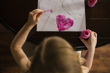 Hohe Winkel Ansicht von Mädchen Färbung Herz Formen auf dem Tisch zu Hause - CAVF46040
