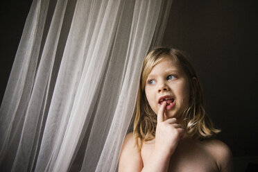 Low angle view of shirtless thoughtful girl looking away while standing by window at home - CAVF46049