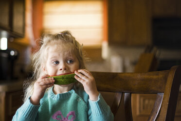 Mädchen schaut weg, während sie eine Wassermelonenscheibe zu Hause isst - CAVF46052