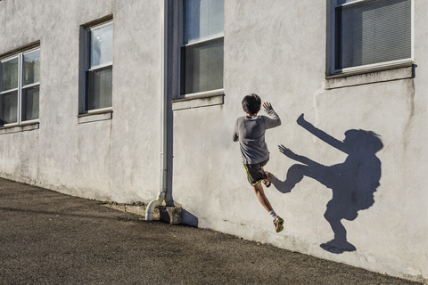 Rückansicht eines Teenagers, der an einem sonnigen Tag über eine Mauer springt, lizenzfreies Stockfoto