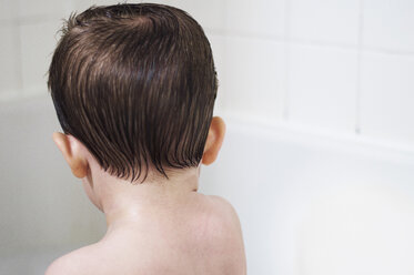 Rückansicht eines Jungen ohne Hemd in einer Badewanne zu Hause - CAVF46085