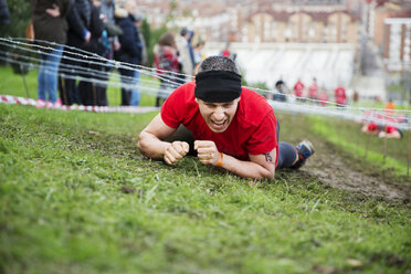 Man shouting and crawling under barbed wires during race - CAVF46137