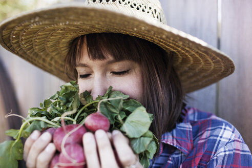 Young woman smelling radishes at organic farm - CAVF46204