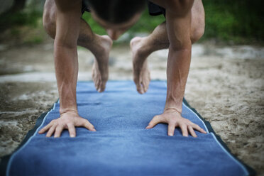 Mann übt Yoga in Krähenstellung auf Übungsmatte - CAVF46223