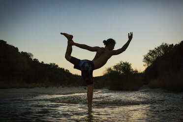Silhouette Mann übt Yoga am Seeufer bei Sonnenuntergang - CAVF46224