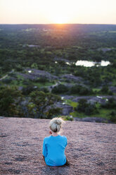 Rear view of woman sitting on mountain during sunset - CAVF46237