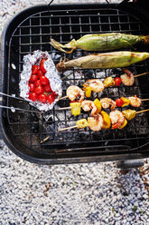 Overhead view of cherry tomatoes with prawns in skewers and corns on barbecue grill - CAVF46295