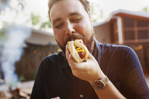 Man eating hot dog at yard stock photo