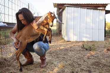 Female farmer injecting goat on field - CAVF46318