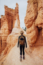 Rear view of woman standing by rock formations - CAVF46377