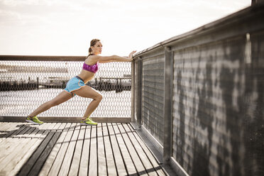 Woman stretching by railing against clear sky - CAVF46432