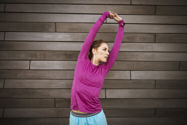 Mid adult woman stretching against wall - CAVF46443