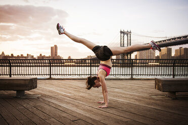 Frau macht Spagat im Handstand auf der Promenade vor der Manhattan-Brücke - CAVF46453