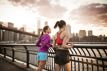 Friends standing at railing by river against sky in city - CAVF46455