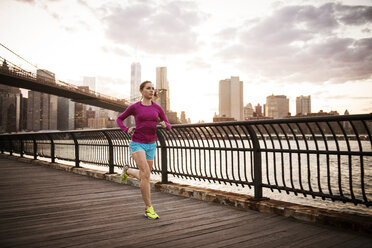 Frau joggt auf der Promenade am East River in der Stadt gegen den Himmel - CAVF46457