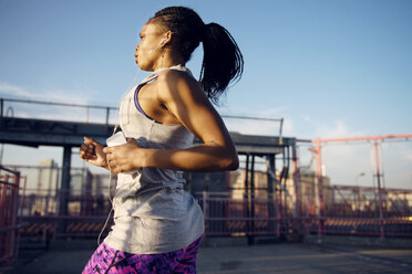 Woman listening music while jogging in city - CAVF46511