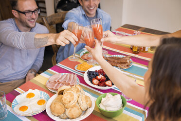 Freunde stoßen beim Essen zu Hause mit einem Getränk an - CAVF46529