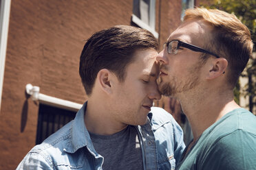 Homosexuelles Paar, das sich umarmt, während es vor dem Haus steht - CAVF46535