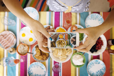 Ausgeschnittenes Bild von Frauenhänden, die Essen am Tisch fotografieren - CAVF46538
