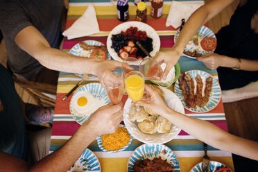 Freunde stoßen mit einem Getränk an, während sie zu Hause essen - CAVF46542