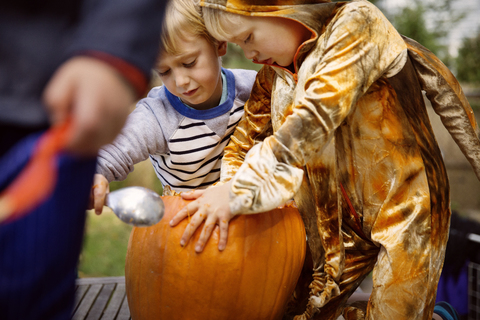 Brüder schnitzen Kürbis im Garten während Halloween, lizenzfreies Stockfoto