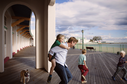Verspielte Familie auf der Promenade vor dem Gebäude gegen den bewölkten Himmel, lizenzfreies Stockfoto