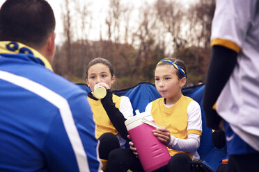 Fußballspieler hören dem Trainer zu, während sie während des Spiels Wasser trinken - CAVF46637