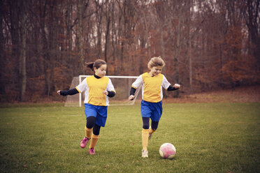 Glückliche Fußballspieler spielen auf einem Feld gegen Bäume - CAVF46648