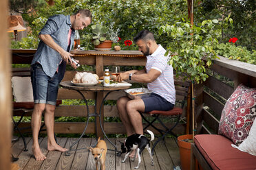 Homosexuelles Paar bereitet Huhn auf dem Balkon mit Chihuahuas zu - CAVF46690