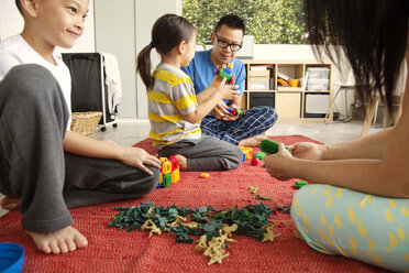 Familie spielt mit Spielzeug auf dem Boden zu Hause - CAVF46696