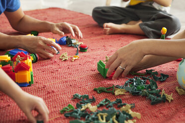 Ausgeschnittenes Bild einer Familie, die zu Hause auf dem Boden mit Spielzeug spielt - CAVF46697